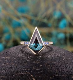 a blue topazte and diamond ring sits atop a rock