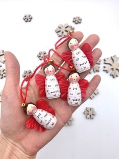 a hand holding some little red and white dolls in it's palm next to snowflakes