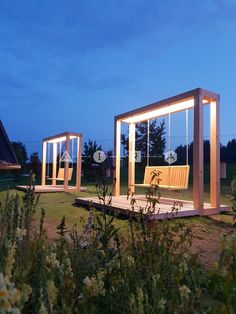 two wooden benches sitting in the middle of a field at night with lights shining on them