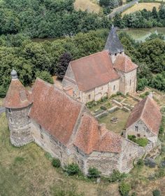 an aerial view of a church in the middle of trees and land, with a river running through it