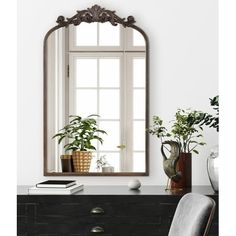 a mirror sitting on top of a dresser next to a chair and potted plant