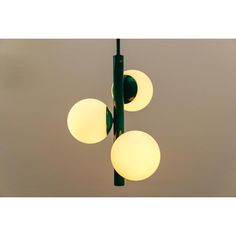 three lights hanging from a green pole with two white balls on each end and one yellow ball at the top