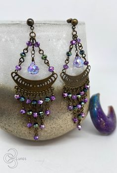 They are earrings with a special and delicate design. They are made with die-cut charms with the phases of the moon, some lilac glass drops and glass beads in purple and green tones. If you have any questions, don't hesitate to write to me. You can see more items from my store here: https://www.etsy.com/es/shop/TresLunasTienda Thank you very much for your visit! :) Purple Metal Chandelier Earrings As Gift, Purple Metal Chandelier Earrings For Gifts, Purple Drop Crystal Earrings, Purple Dangle Chandelier Earrings, Purple Metal Chandelier Dangle Earrings, Purple Crystal Drop Earrings, Purple Dangle Crystal Earrings, Hypoallergenic Purple Bohemian Earrings, Purple Metal Dangle Chandelier Earrings