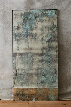 an abstract painting is displayed on a wooden floor next to a white and blue wall