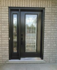 a black double door with glass on the side of a brick wall and concrete floor