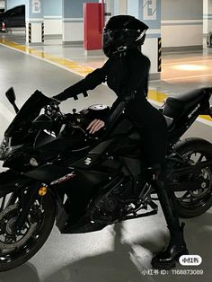 a woman in black riding on the back of a motorcycle