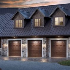 a house with three garages and lights on the side of it at night in front of a cloudy sky