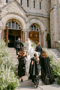 the bride and groom are walking down the stairs to their wedding ceremony in front of an old church