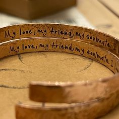 three wooden bracelets with writing on them sitting on top of a table next to a box