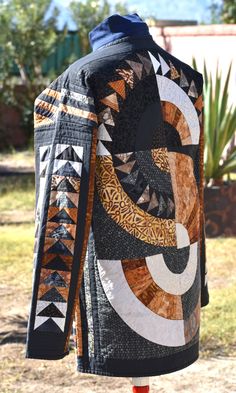 a jacket with an abstract design on it sitting in front of some trees and grass