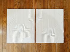 two pieces of white paper sitting on top of a wooden floor next to each other