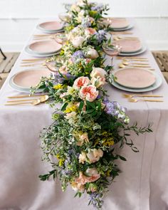 a long table with plates and flowers on it