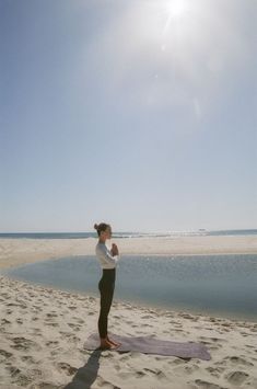 a woman is doing yoga on the beach