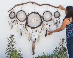 a woman standing in front of a wall hanging dream catchers