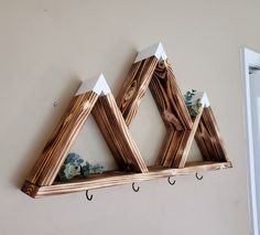 three wooden triangle shaped shelves with hooks on them