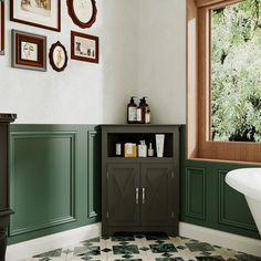 a bathroom with green and white tile flooring next to a bathtub in front of a window