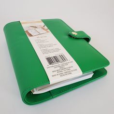 a green leather notebook with a barcode on the front cover and a button in the middle