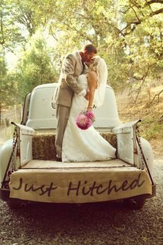 a bride and groom kissing in the back of an old pickup truck with just hitched written on it