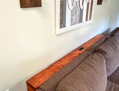 a brown couch sitting next to a wall with pictures on it's walls above it