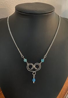 This is a beautiful and unique turquoise pendant necklace.  The central feature for the necklace is a spiral heart shaped design made with silver plated non tarnish wire. Suspended from the bottom loop of the heart is a beautiful faceted turquoise bead with delicate silver plated beads at the top and bottom. Either side of the heart are spherical turquoise crackle glass beads, again with delicate silver plated beads either side. This entire central portion of the necklace is approximately 13 cm in length. The chain to the necklace may be either silver plated oval trace chain or 925 sterling silver belcher chain. You may choose from the options. The entire length of the necklace is 18 inches ( 45 cm ).  The necklace comes wrapped and presented in a pink sugar and spice gift box making the p Blue Spiral Necklace For Gift, Blue Nickel-free Heart Pendant Jewelry, Blue Sterling Silver Wire Wrapped Necklace, Blue Spiral Sterling Silver Jewelry, Mothers Day Necklace, Heart Pendent, February Birthstone Necklace, Blue Pendant Necklace, Spice Gift