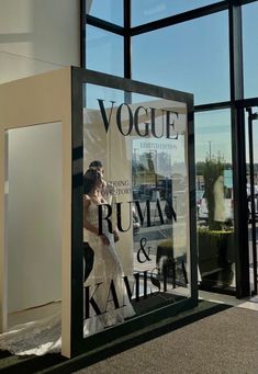 a woman in a wedding dress is reflected in the window of a fashion store front