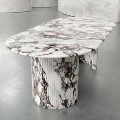 a marble table sitting on top of a floor next to two white walls in an empty room