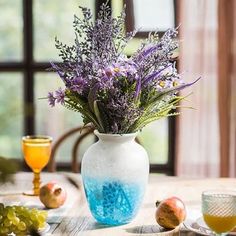 a vase filled with purple flowers sitting on top of a table next to plates and glasses