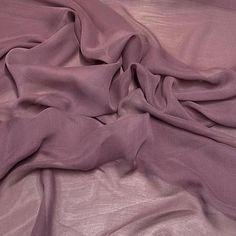 an unmade bed with purple sheets and pillows