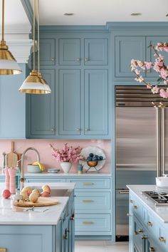 a kitchen with blue cabinets and marble counter tops, gold accents on the hoods