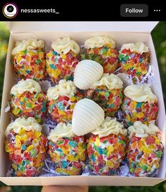 a box filled with lots of cupcakes covered in white frosting and sprinkles