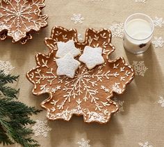 two cookies and a glass of milk are on a table with snowflakes