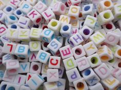 letters and numbers made from plastic beads on a white table top with the word abc written in multicolored letters