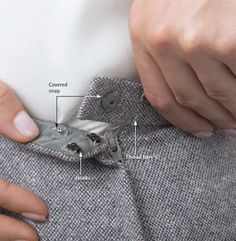 a person with their hand on the pocket of a jacket that has buttons attached to it