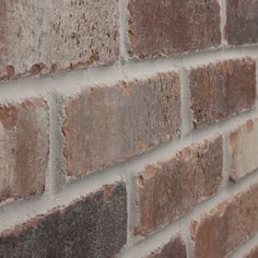 a brick wall that is made out of red and gray bricks with white mortar on it