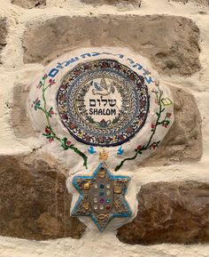 a white stone wall with a blue and gold star on it's side, in hebrew writing