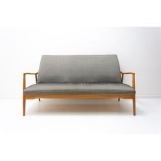 a gray couch sitting on top of a white floor next to a wooden frame chair