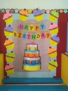 a birthday cake with cupcakes and candles on it sitting in front of a sign that says happy birthday