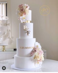 a three tiered wedding cake with flowers on top and the words pf written in gold