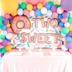 there is a two sweet sign on the table with balloons and confetti around it