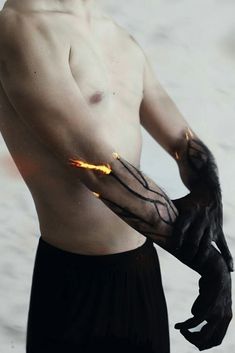 a shirtless man holding a bird in his right hand while standing on the beach