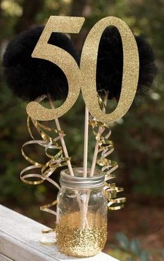 a mason jar filled with gold glitter and black pom - poms sitting on top of a wooden table