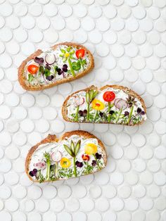 three pieces of bread with different types of food on them sitting on a white surface