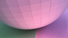 a large pink ball sitting on top of a green floor next to a white wall