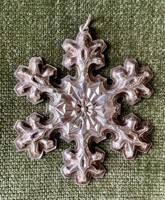 a silver snowflake ornament on a green carpet