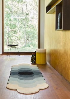 an area rug on the floor in front of a large window with a view of trees