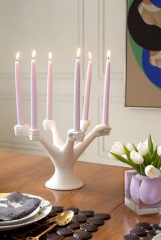 a table topped with a vase filled with white flowers next to a bunch of lit candles