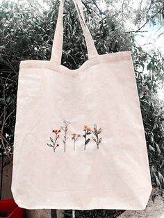 a tote bag with flowers on it hanging from a tree