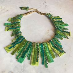 a green and yellow necklace on a marble surface