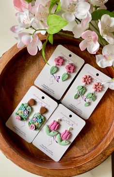 four small buttons are sitting on top of a wooden tray next to some pink flowers