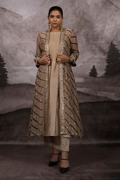 Bronze and greyish gold three fourth sleeves front open shrug with all over leheriya tie dye wave pattern, geometric embellishments and adorned with hand embroidered leaf motifs using metallic threads, pitta and bead work. Paired with a crew neck kurta with intricate jaal hand embroidery on the neck yoke and a matching embroidered palazzo pant. - Aza Fashions Elegant Front Open Dupatta With Resham Embroidery, Elegant Long Sleeve Choli For Transitional Season, Elegant Front Open Dupatta With Zari Work, Elegant Designer Festive Outerwear, Elegant Festive Designer Outerwear, Elegant Chanderi Bandhgala For Festive Occasions, Elegant Festive Chanderi Bandhgala, Elegant Designer Outerwear For Diwali, Elegant Festive Outerwear With Dabka Work